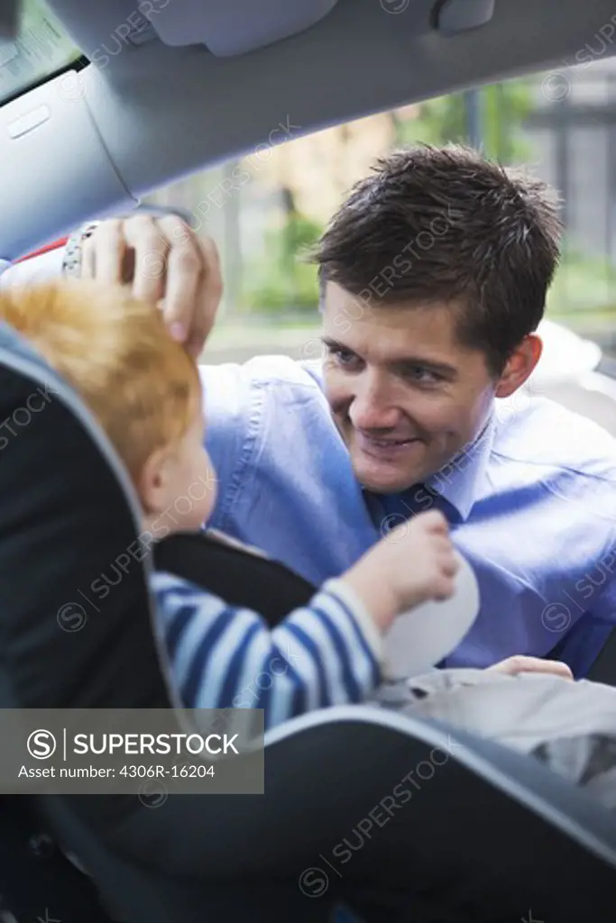 Father fastening his son in a car safety-seat, Stockholm, Sweden.