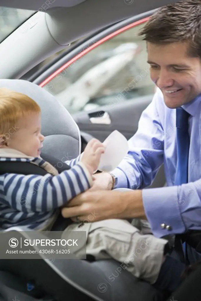 Father fastening his son in a car safety-seat, Stockholm, Sweden.