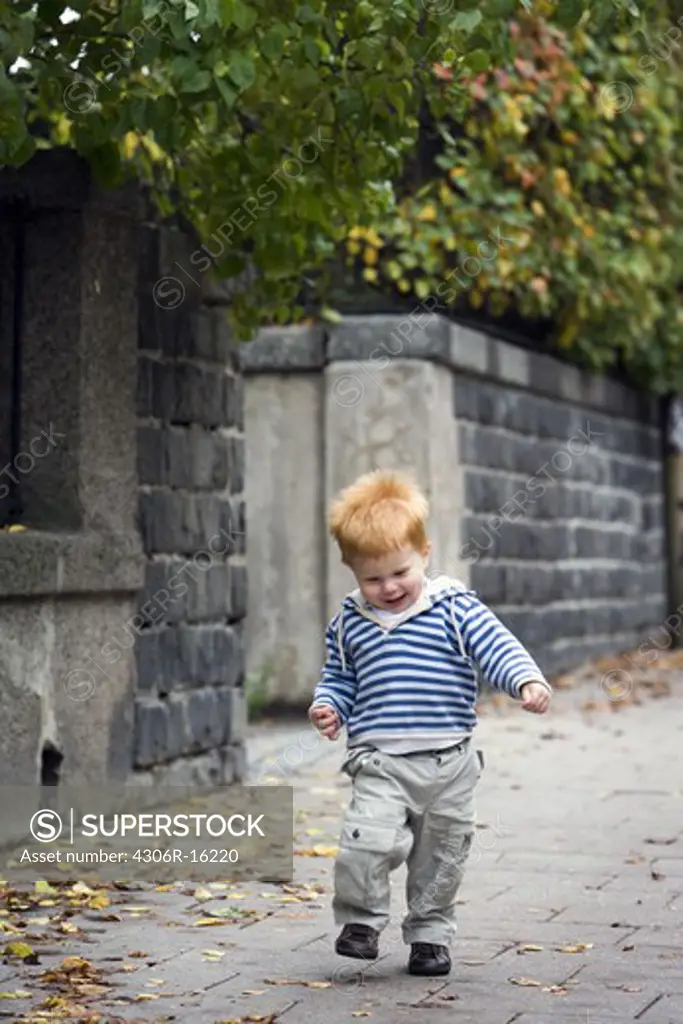 A little boy running on the pavement, Stockholm, Sweden.
