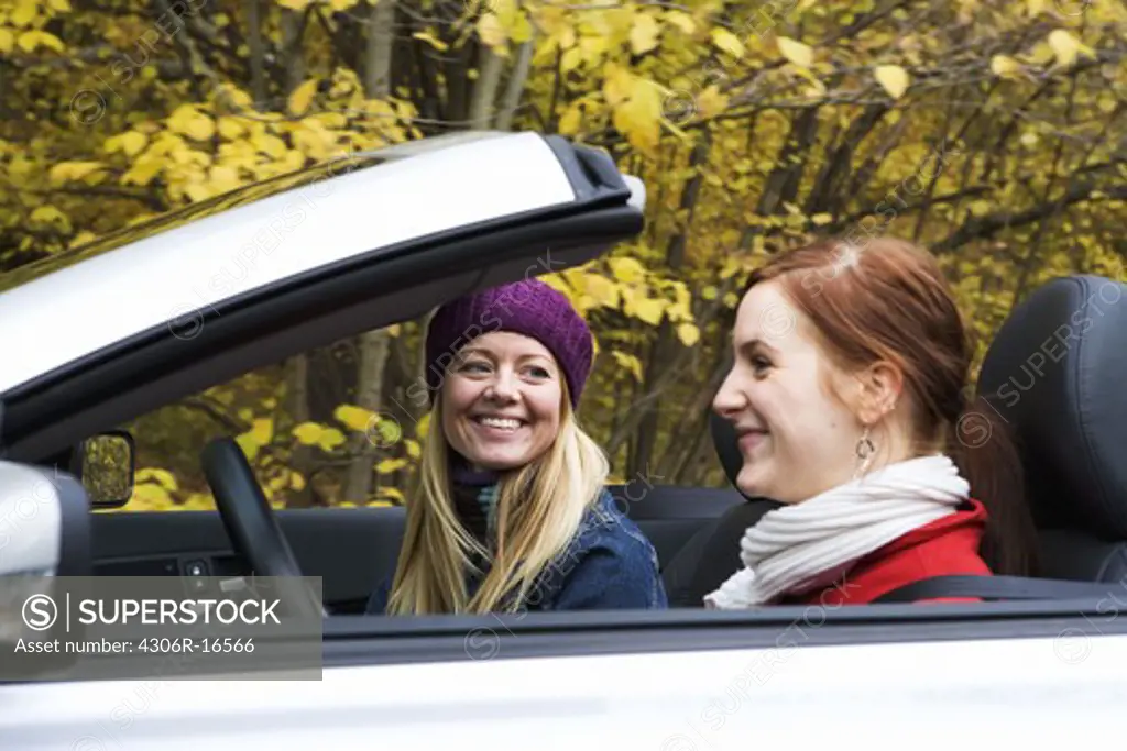 Two young women driving a cabriolet an autumn day, Sweden.