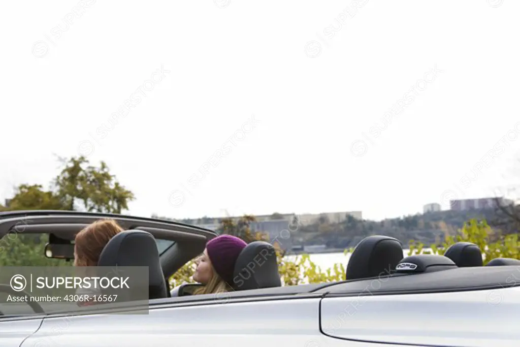 Two young women driving a cabriolet an autumn day, Sweden.