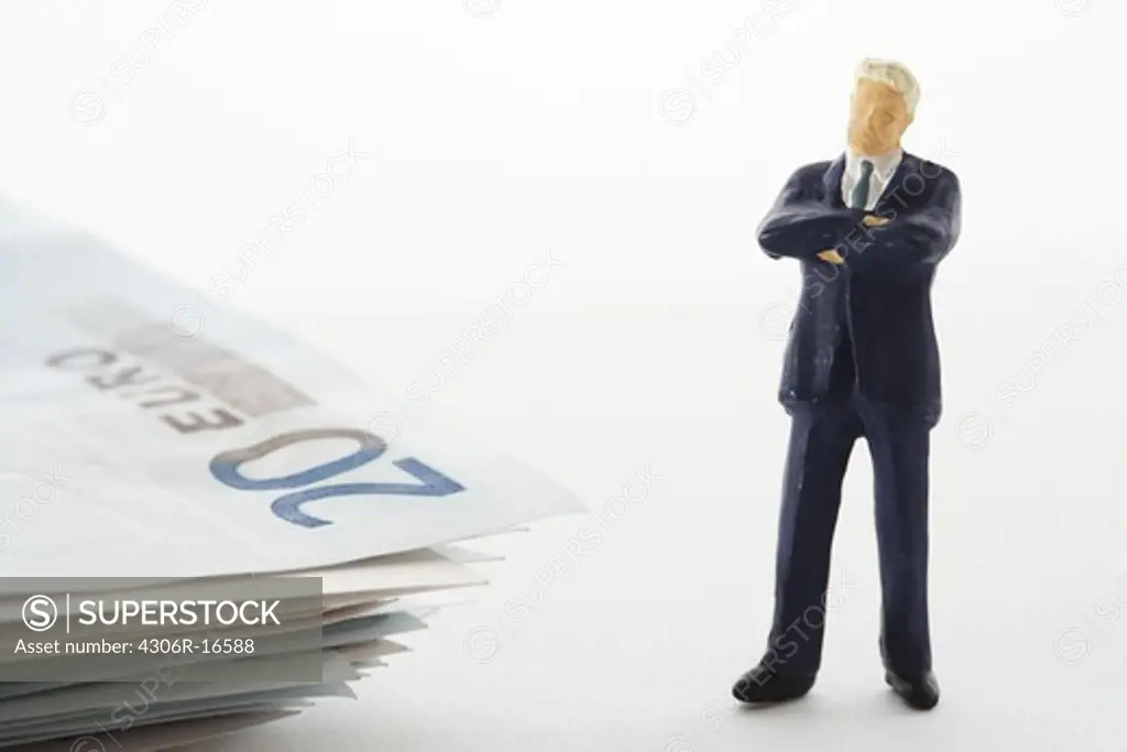 A figure in the shape of a man standing next to a bundle of Euro bills.