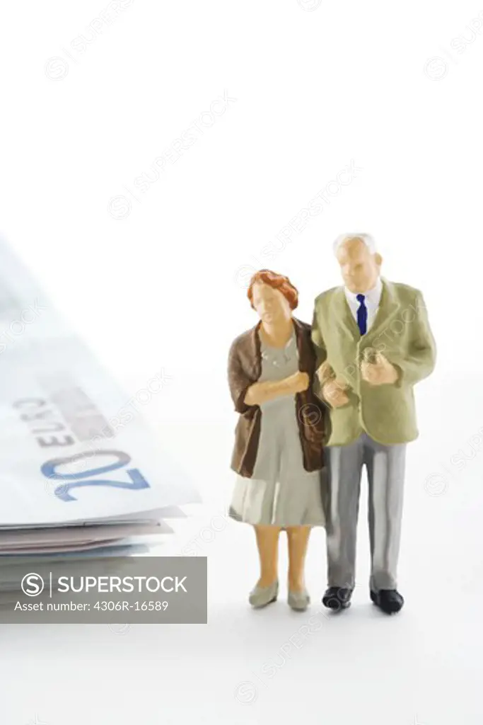Figures in the shape of a senior couple standing next to a bundle of notes.