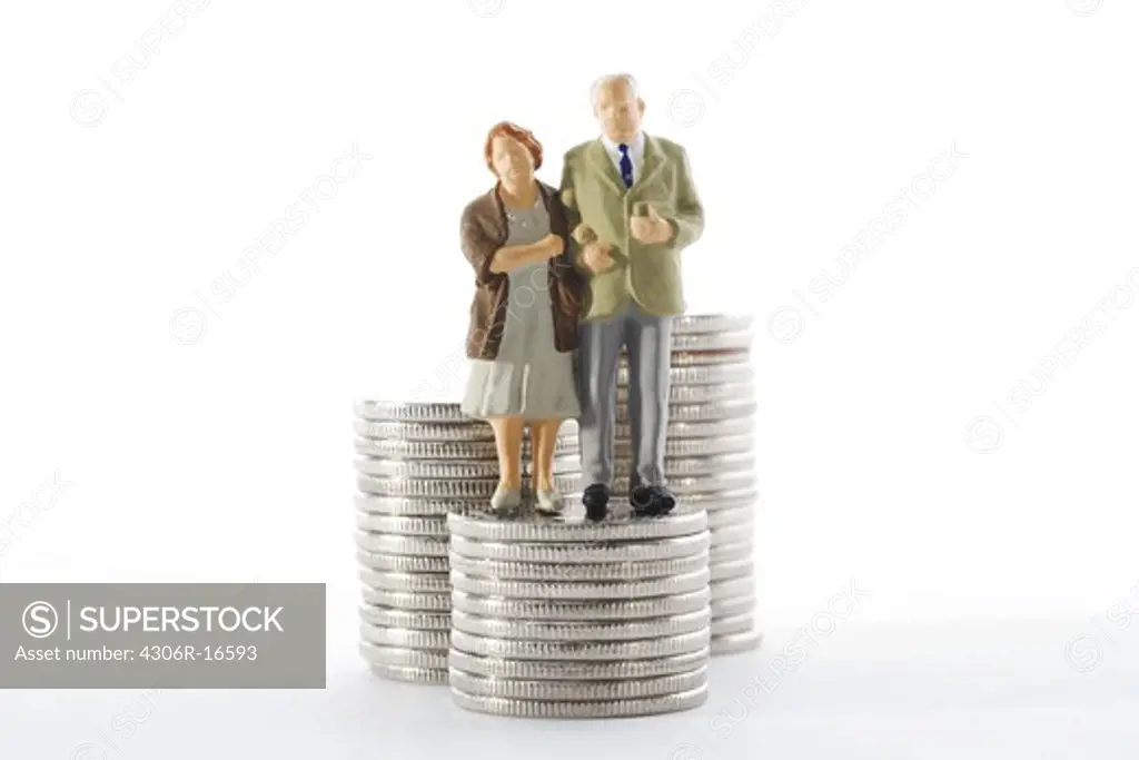 Figures in the shape of a senior couple standing by coins.