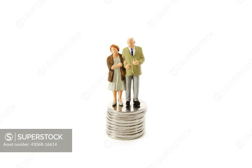 Senior couple standing on pile of coins.