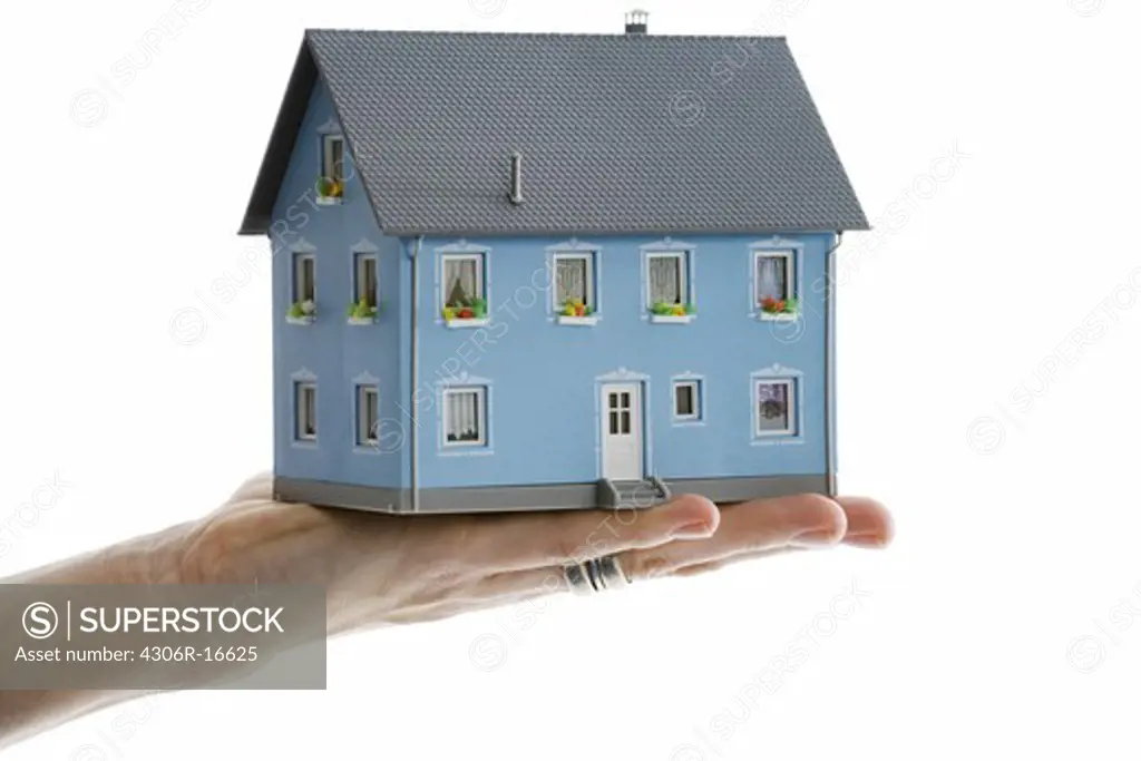 A hand holding a miniature house.