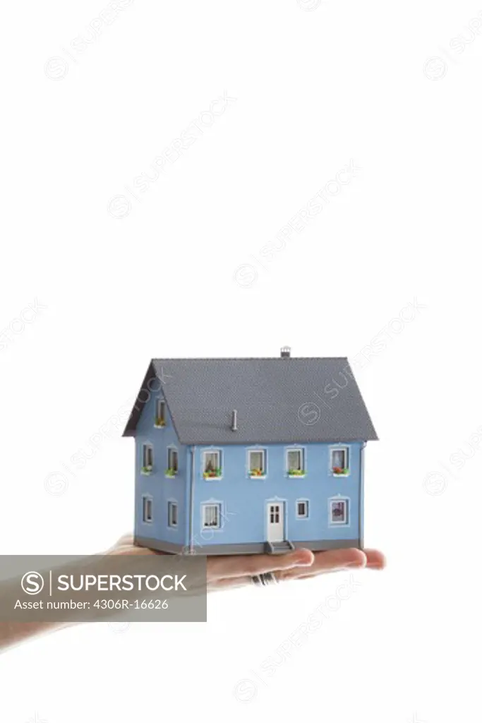 A hand holding a miniature house.