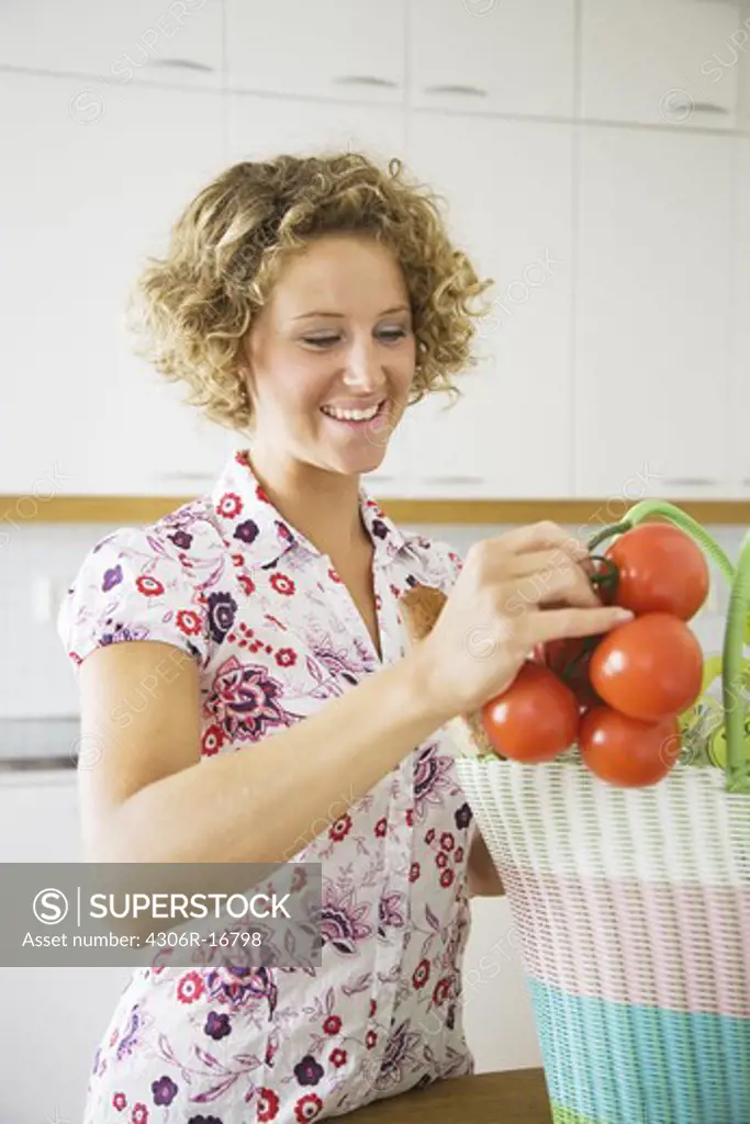 A woman taking out tomatoes from a bag, Sweden.