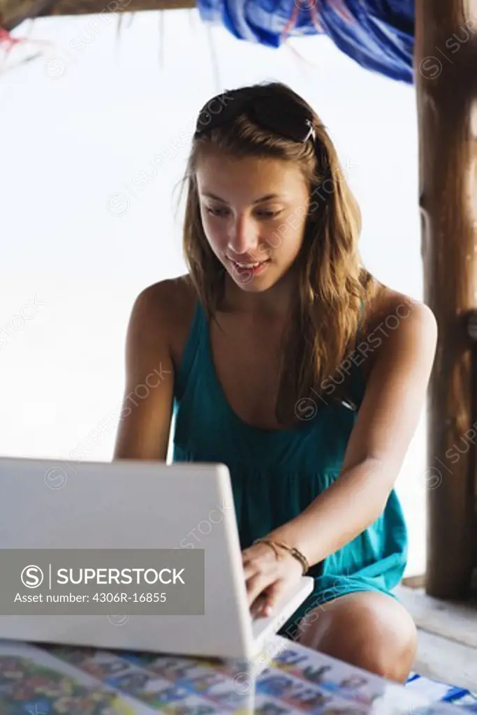 A Scandinavian teenage girl with a laptop by the sea, Thailand.