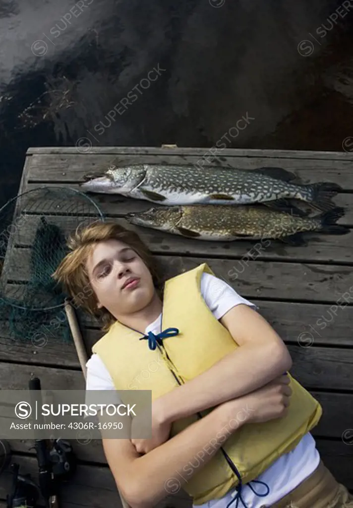 A boy with a fish on a jetty, Sweden.