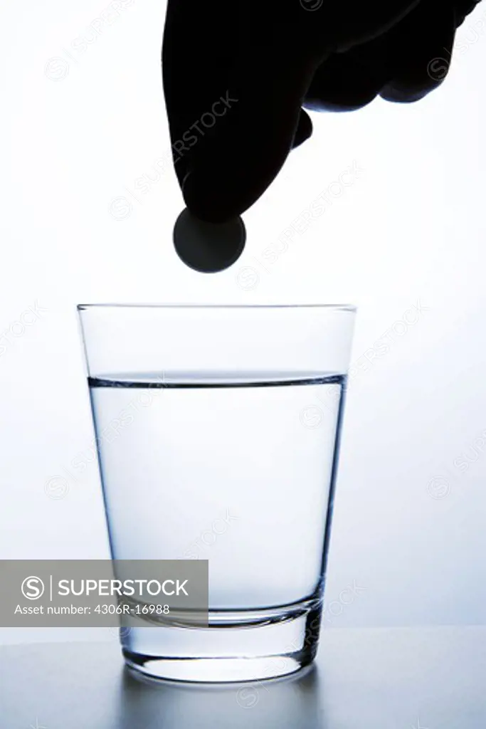 An effervescent tablet and a glass of water, close-up.