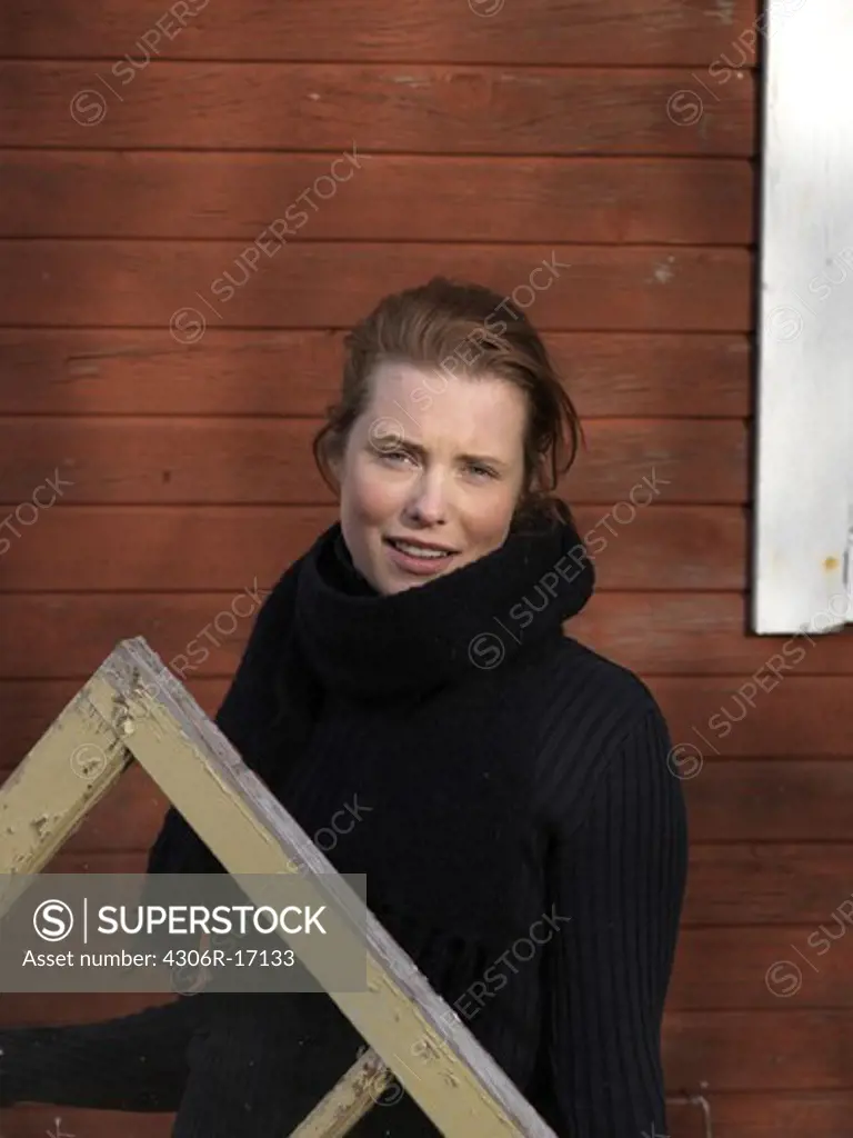 A young woman holding a window frame, Sweden.