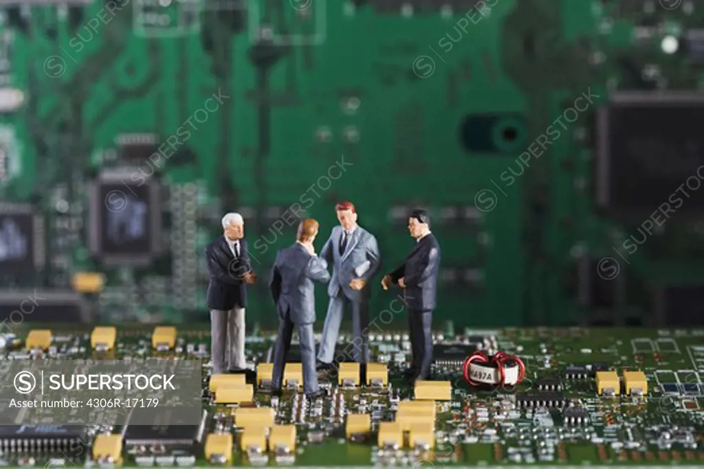 Figures in the shape of business men standing in a printed circuit card.