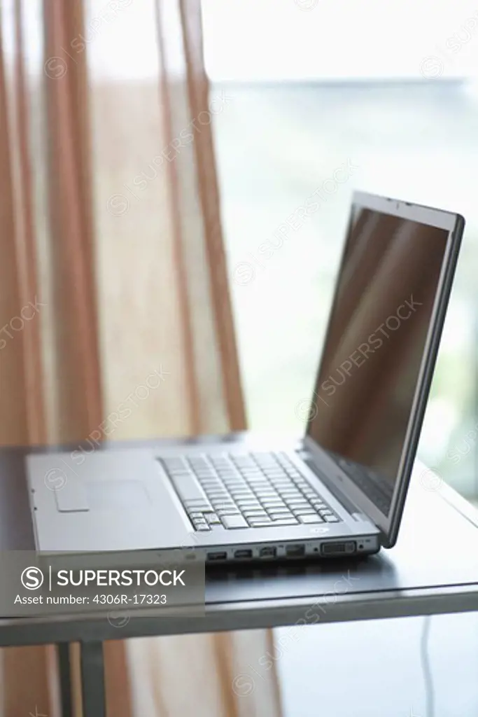 A laptop by a window.