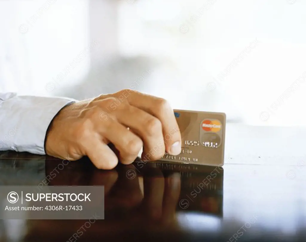 The hand of a man holding a credit card.