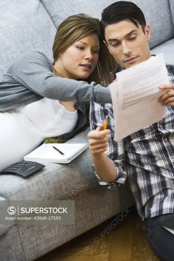 A pregnant woman and a man discussing their home finances, Sweden.