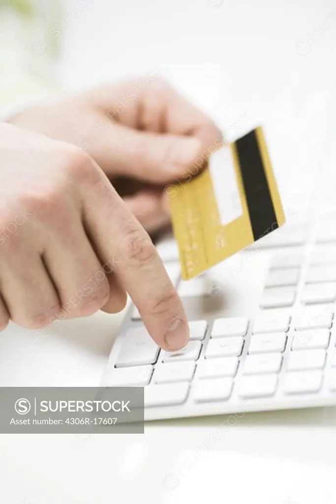 A hand holding a credit card and using a keyboard, Sweden.