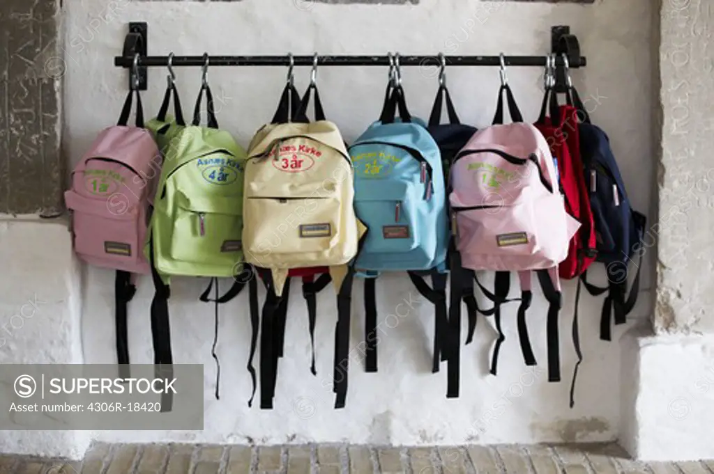 Backpacks hanging on a wall.