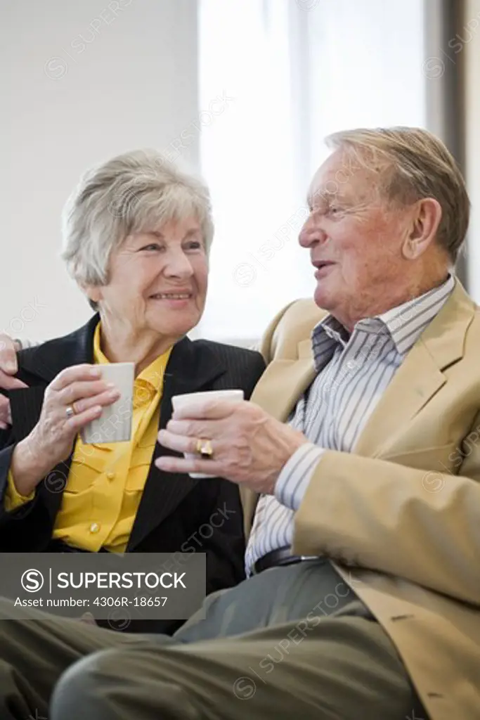 An old couple holding cups of coffee, Sweden.