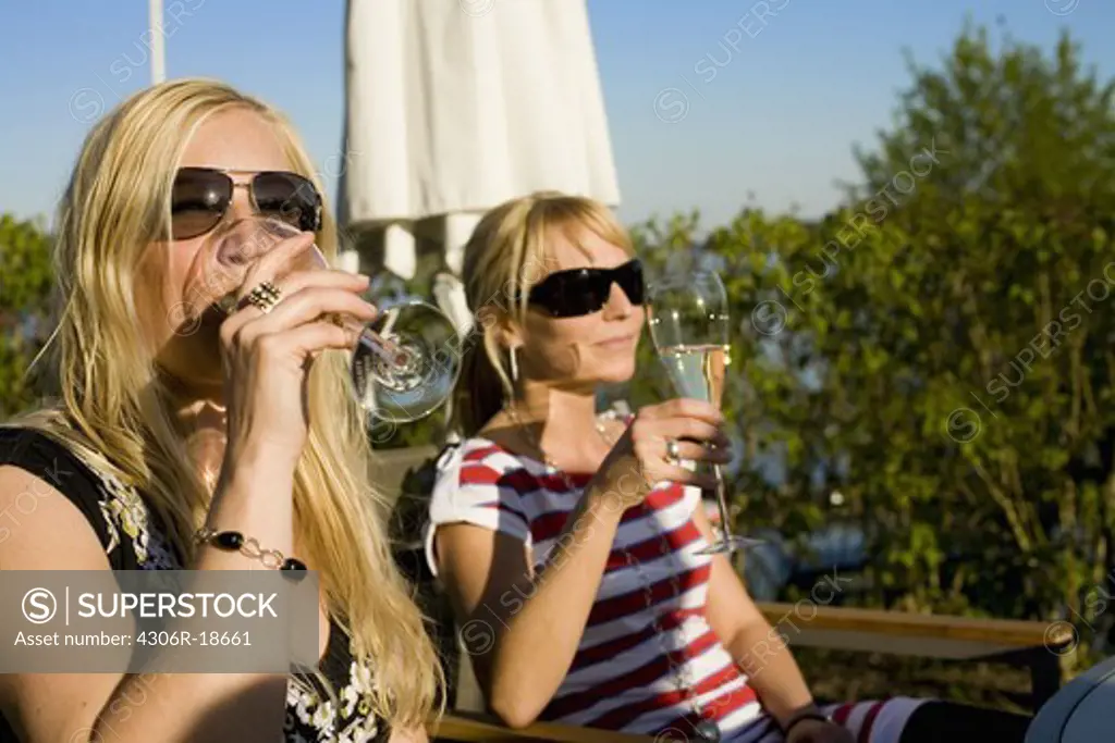 Two women drinking wine in the sun, Sweden.
