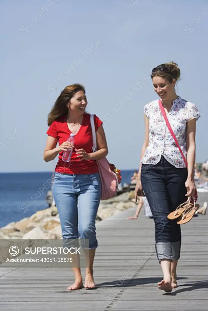 Two women walking on a jetty, Malmo, Skane, Sweden.