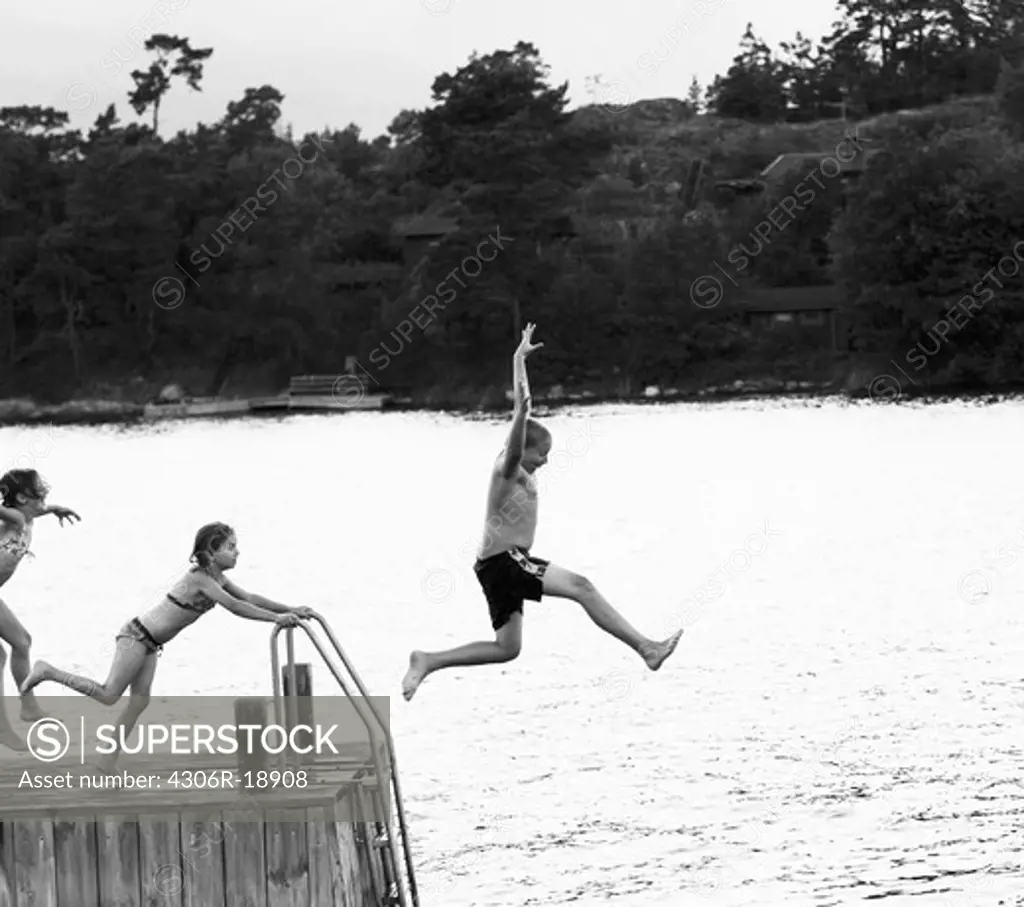 Three children jumping from a jetty, Sweden.