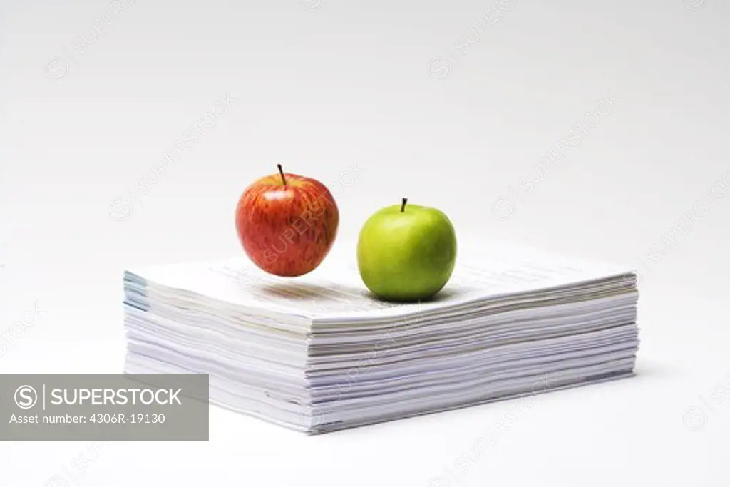 Two apples on a stack of paper, close-up.