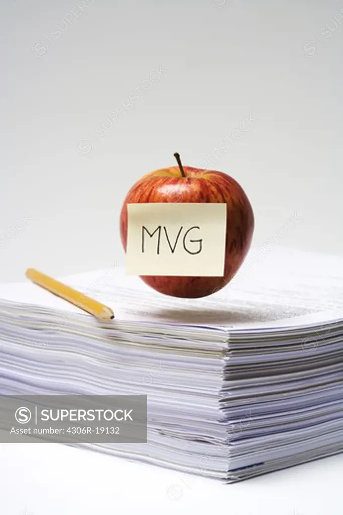 An apple on a stack of paper, close-up.