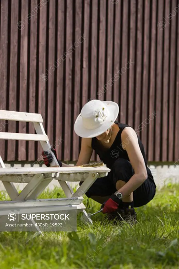 Woman working on a piece of outdoor furniture, Sweden.