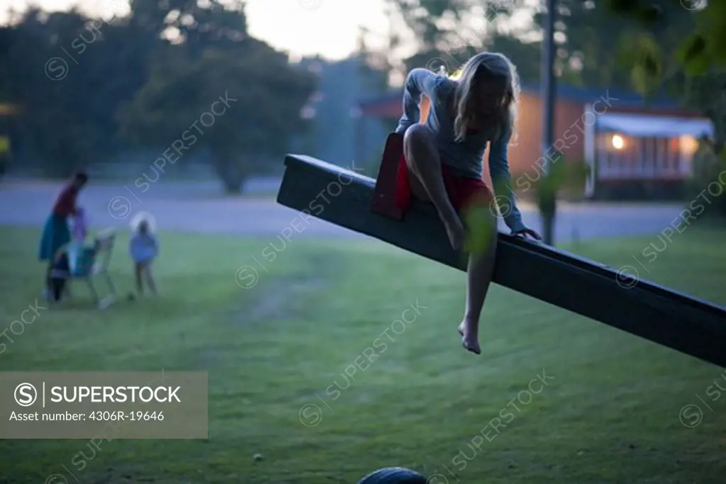 Mother and daughters on a playground at dusk, Sweden.