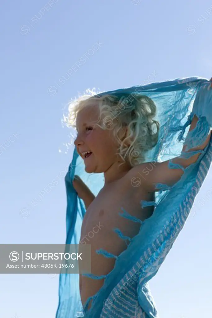 A girl with a turquoise scarf against a blue sky, Sweden.