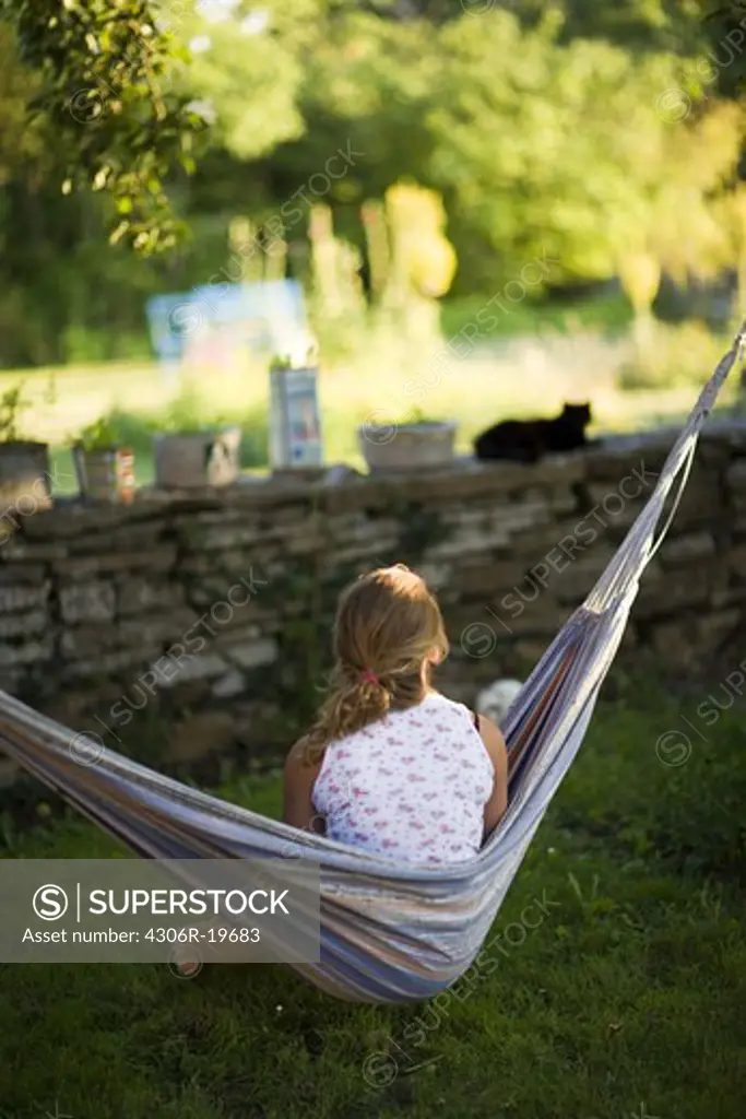 Teenage girl sitting in a hammock, Sweden.