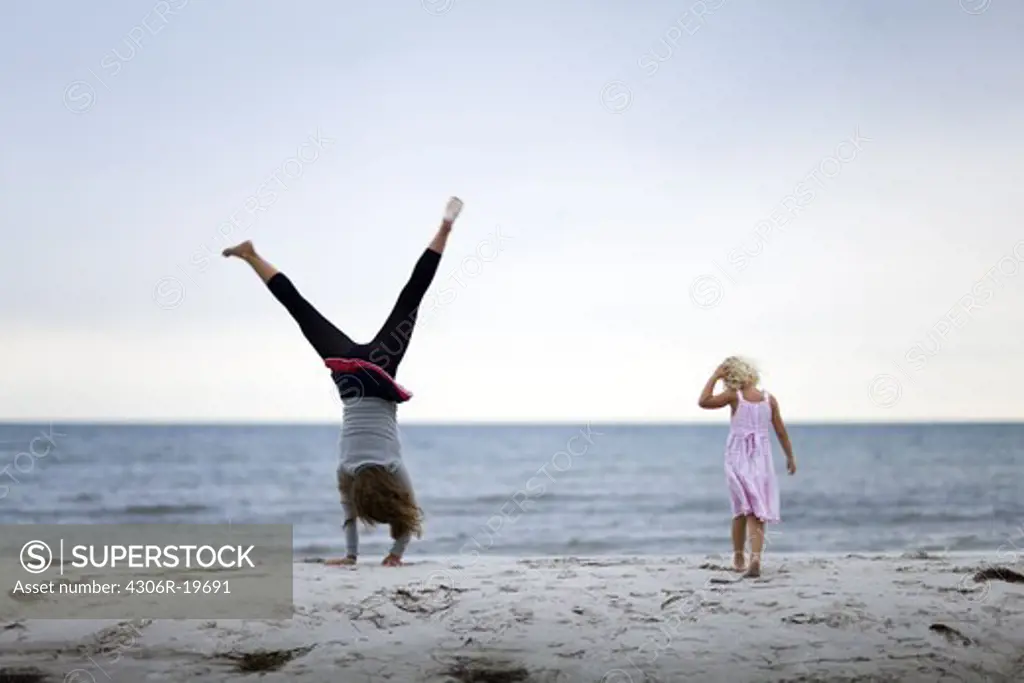 Two girls playing on a beach by the sea, Sweden.