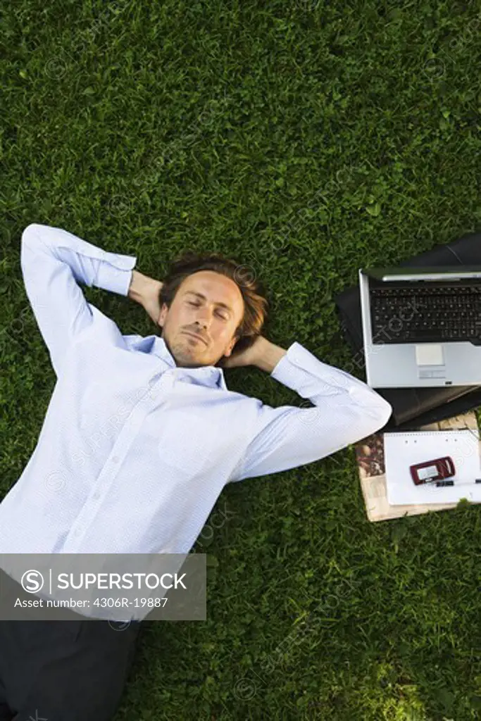 A man with a laptop in a park, Sweden.