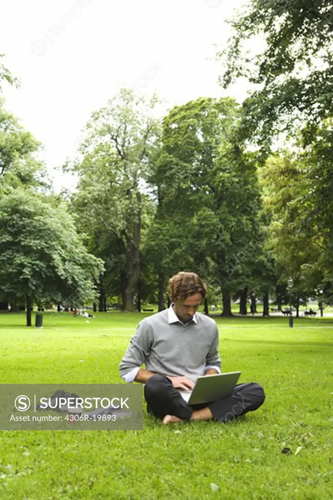A man with a laptop in a park, Sweden.