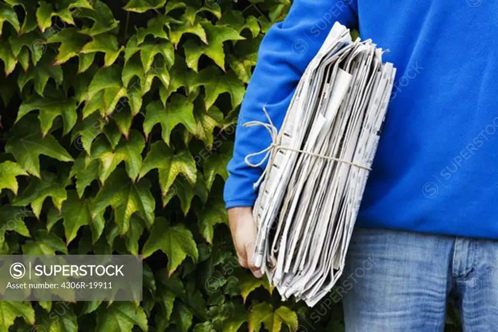 A man holding newspapers for recycling.