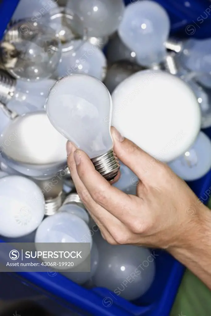 A man holding light bulbs for recycling.