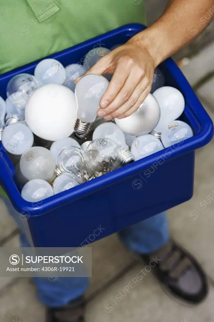 A man holding light bulbs for recycling.