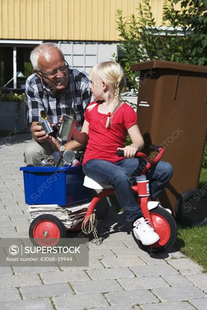 Grandfather and granddaughter by a dustbin, Sweden.