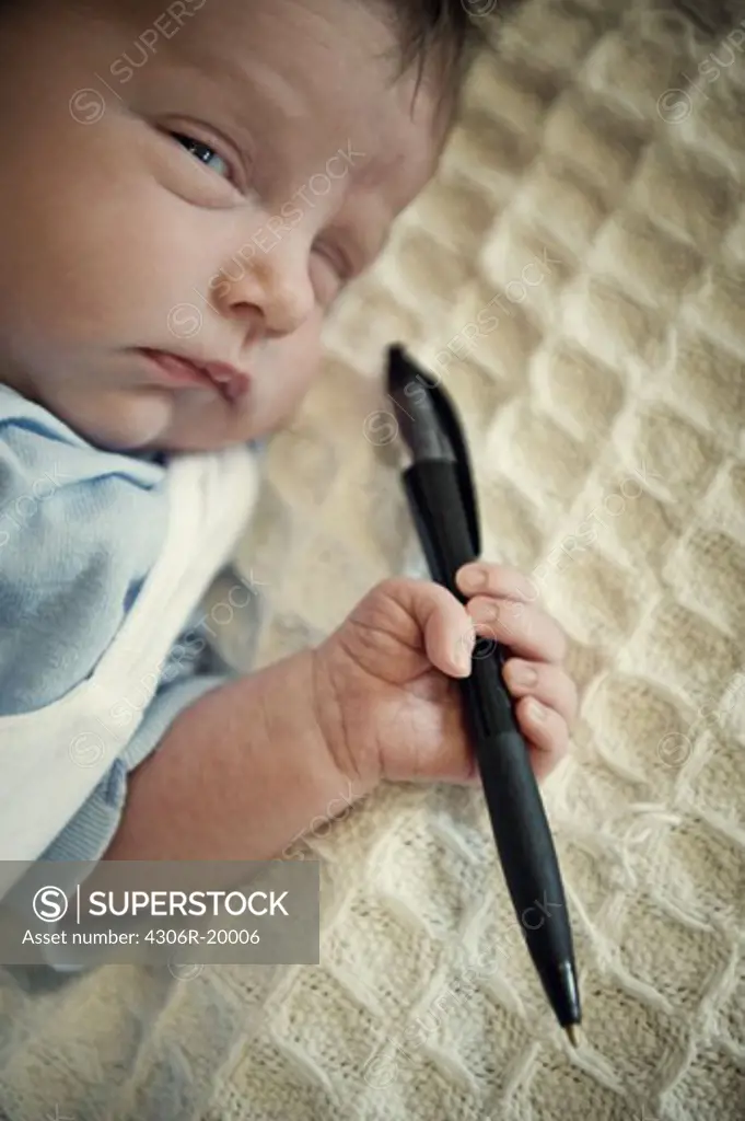Newborn child holding a pen, Sweden.