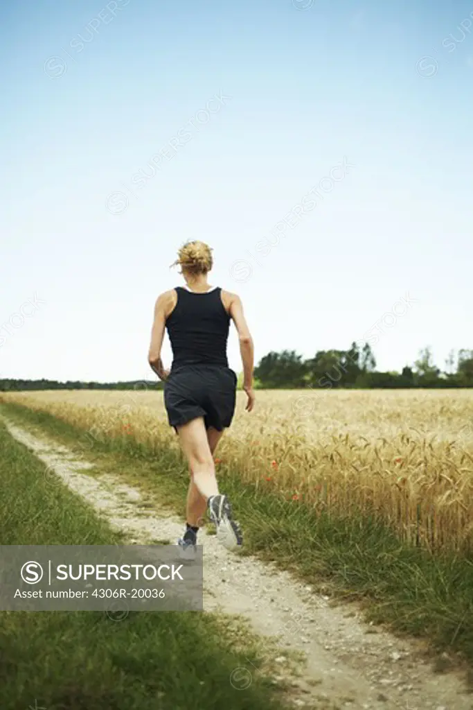 Woman jogging in an open landscape, Sweden.