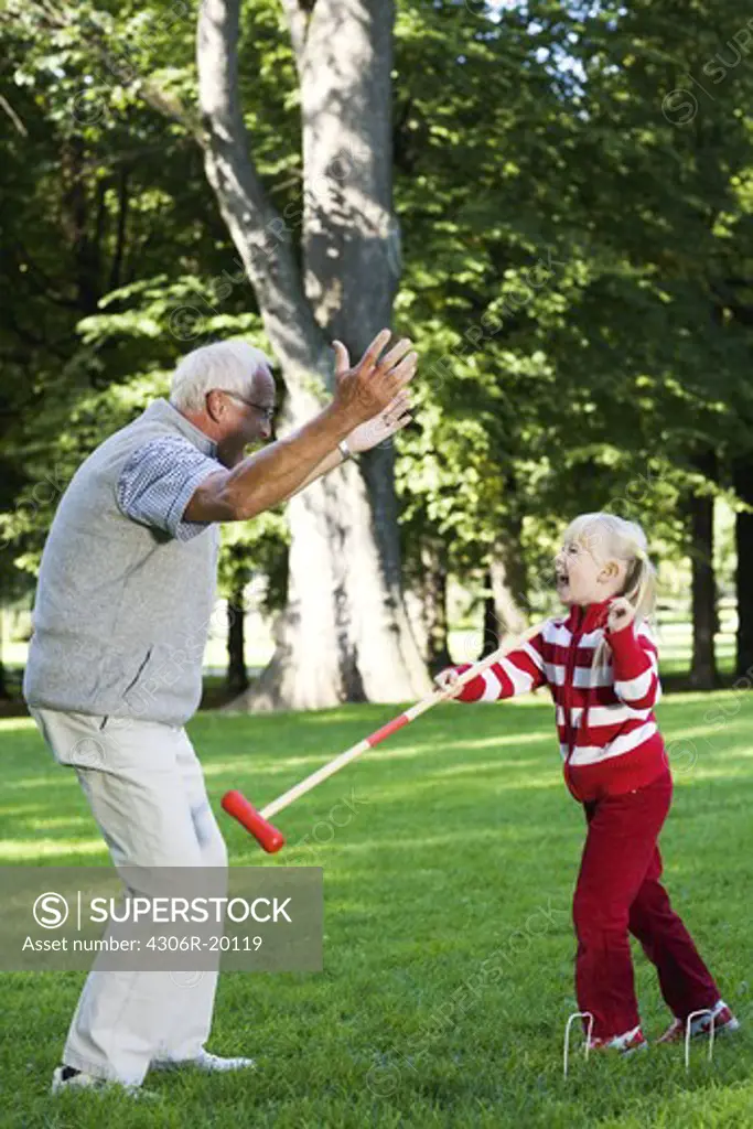 Girl and senior man playing croquet in the park, Sweden.