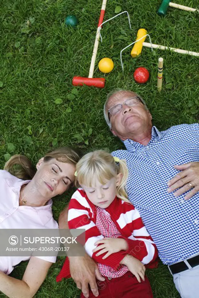 A senior man, girl and woman resting in the park, Sweden.