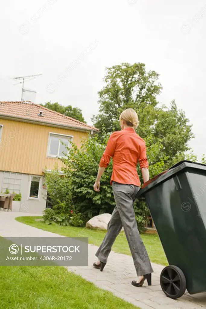 A woman pulling a refuse bin, Sweden.