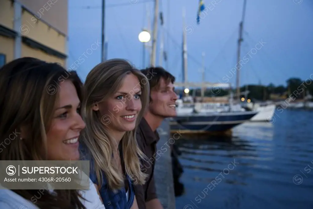 Three friends sitting on a quay-edge, Stockholm, Sweden.