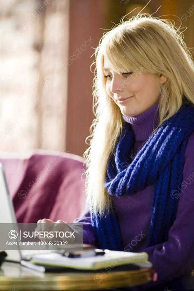 Young woman sitting in a cafe using a laptop, Sweden.