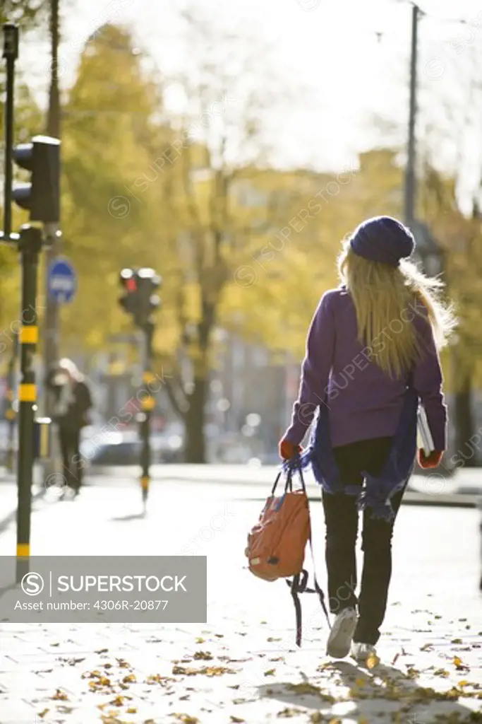 A woman walking in street in autumn, Stockholm, Sweden.