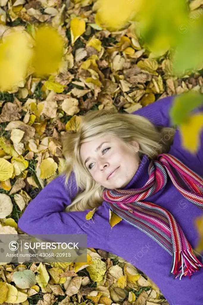 A woman resting on autumn leaves, Sweden.