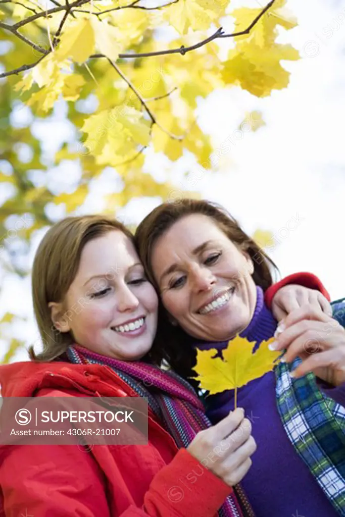 Mother and daughter holding a maple leaf, Sweden.