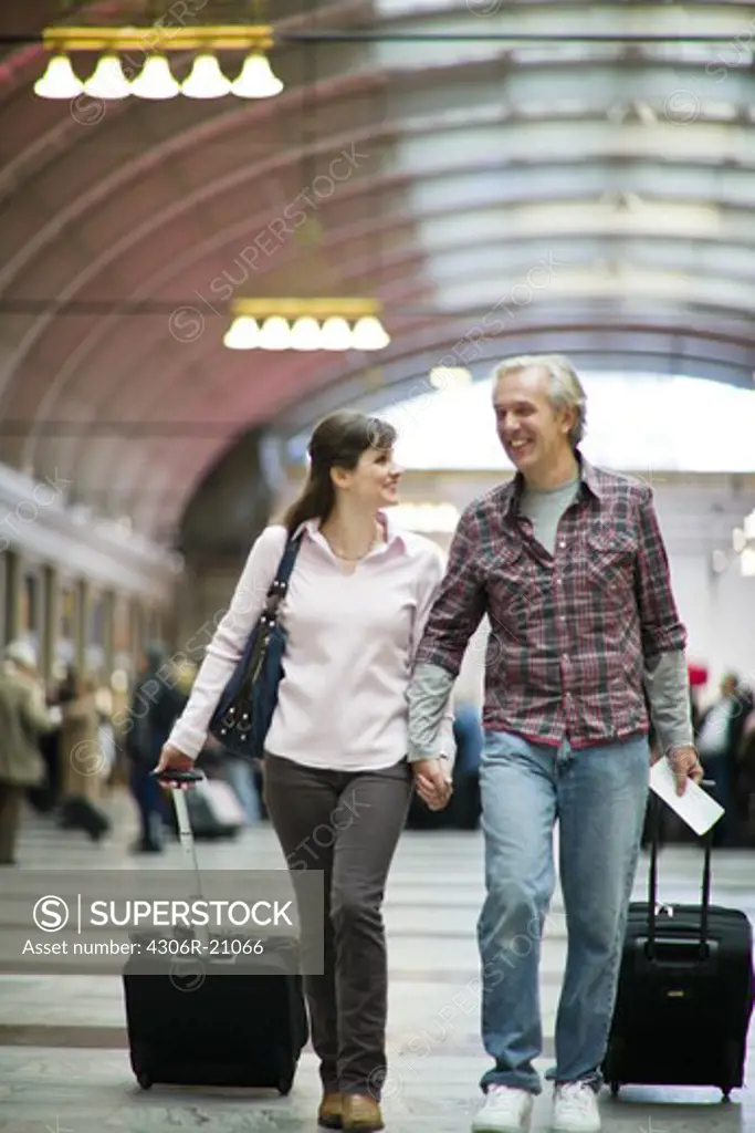 A couple with suitcases at a railway station,